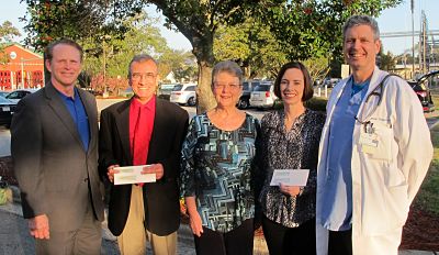 Posing with the checks are Dosher CEO Tom Siemers; Brunswick Adult Medical Clinic Medical Director Dr. Zia Hashemi and Clinical Coordinator Annette Laska; New Hope Clinic Executive Director Sheila Roberts; and Dr. Palagruto.