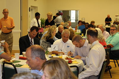 Guests write checks and fill out pledge cards at a Dosher Foundation fundraising event.