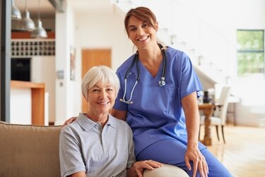 Healthcare provider sitting on an armchair next to a smiling patient who is sitting in the chair.